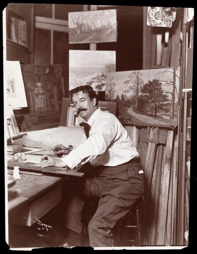 Portrait of Ernest Gross, scenic designer, sitting in his studio at his drafting table, 1908-9 by Byron Company
